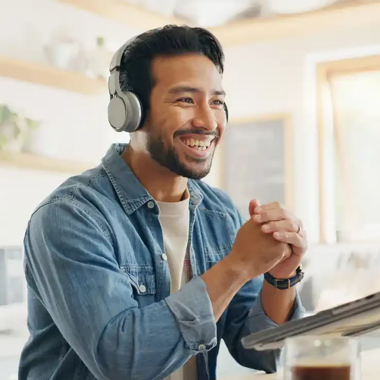 best value content marketing australia.jpg Smiling content marketer with hands together in front of laptop with headphone on.