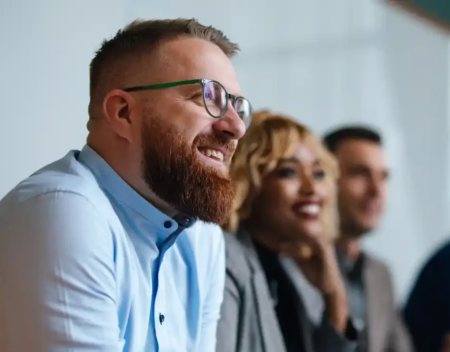 best website content writer australia Mortgage broker with beard at a meeting with content writers, smiling inside office setting.