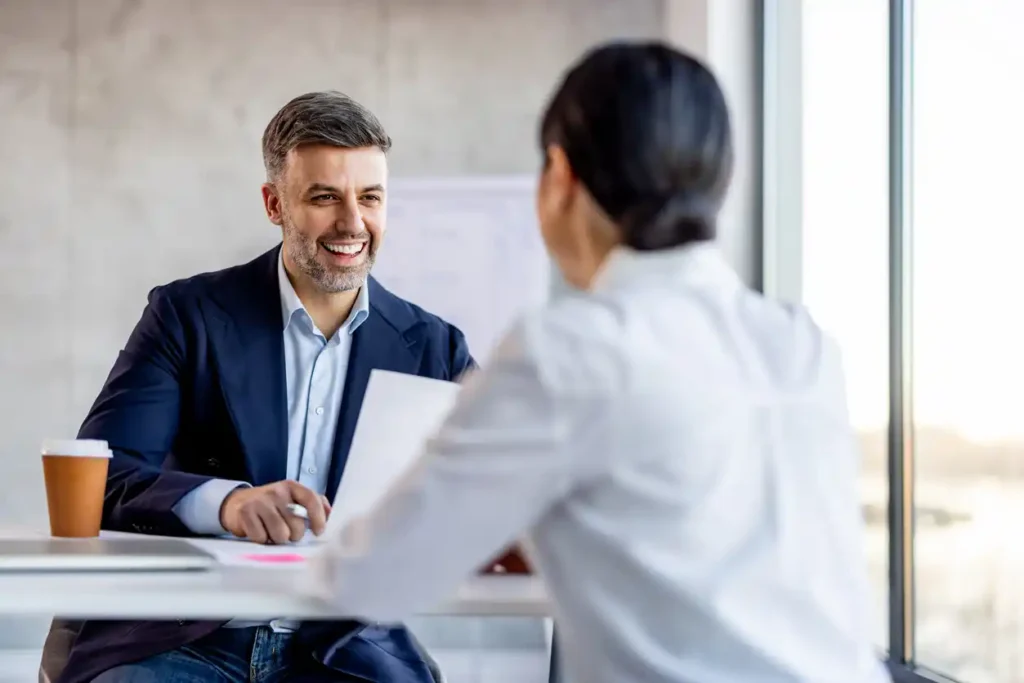Mortgage broker speaking to compliance officer in office with views.