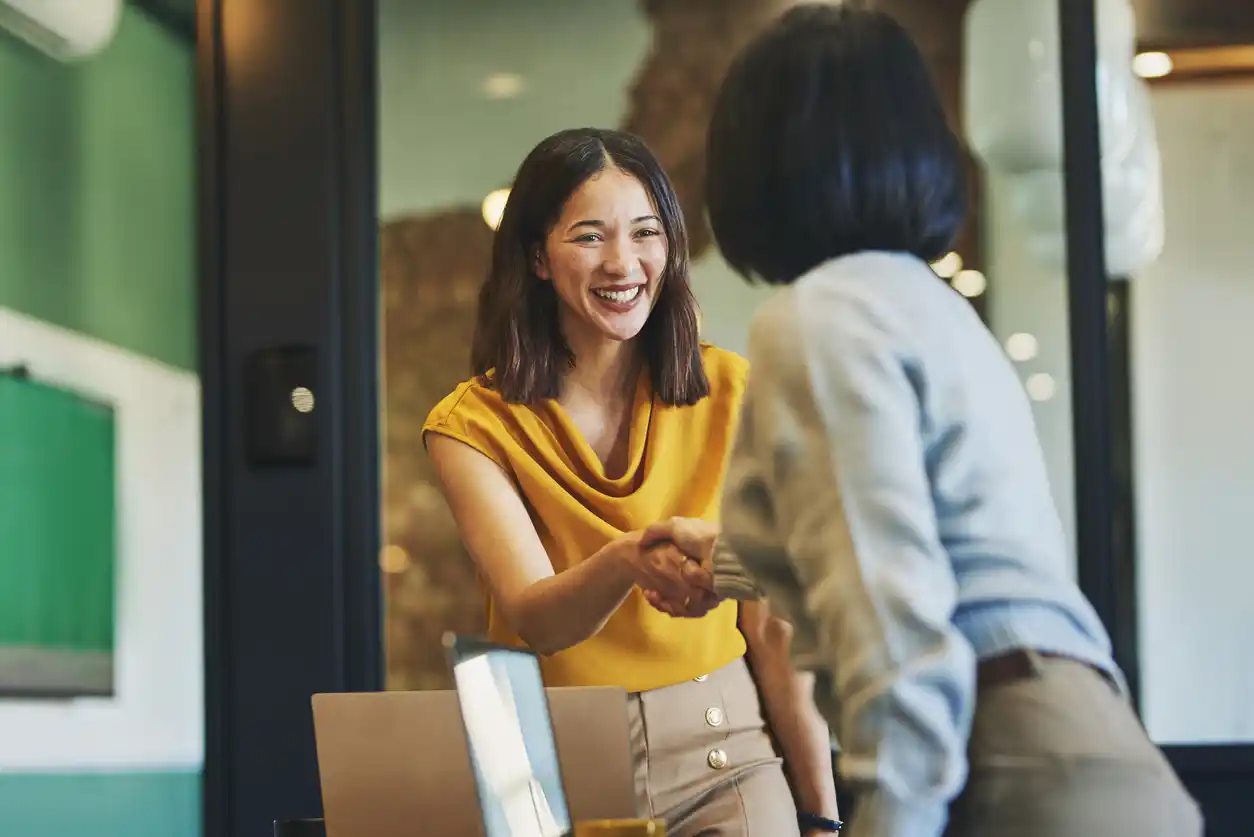 website content writing australia Female content writer in professional setting shaking hands with female finance expert.