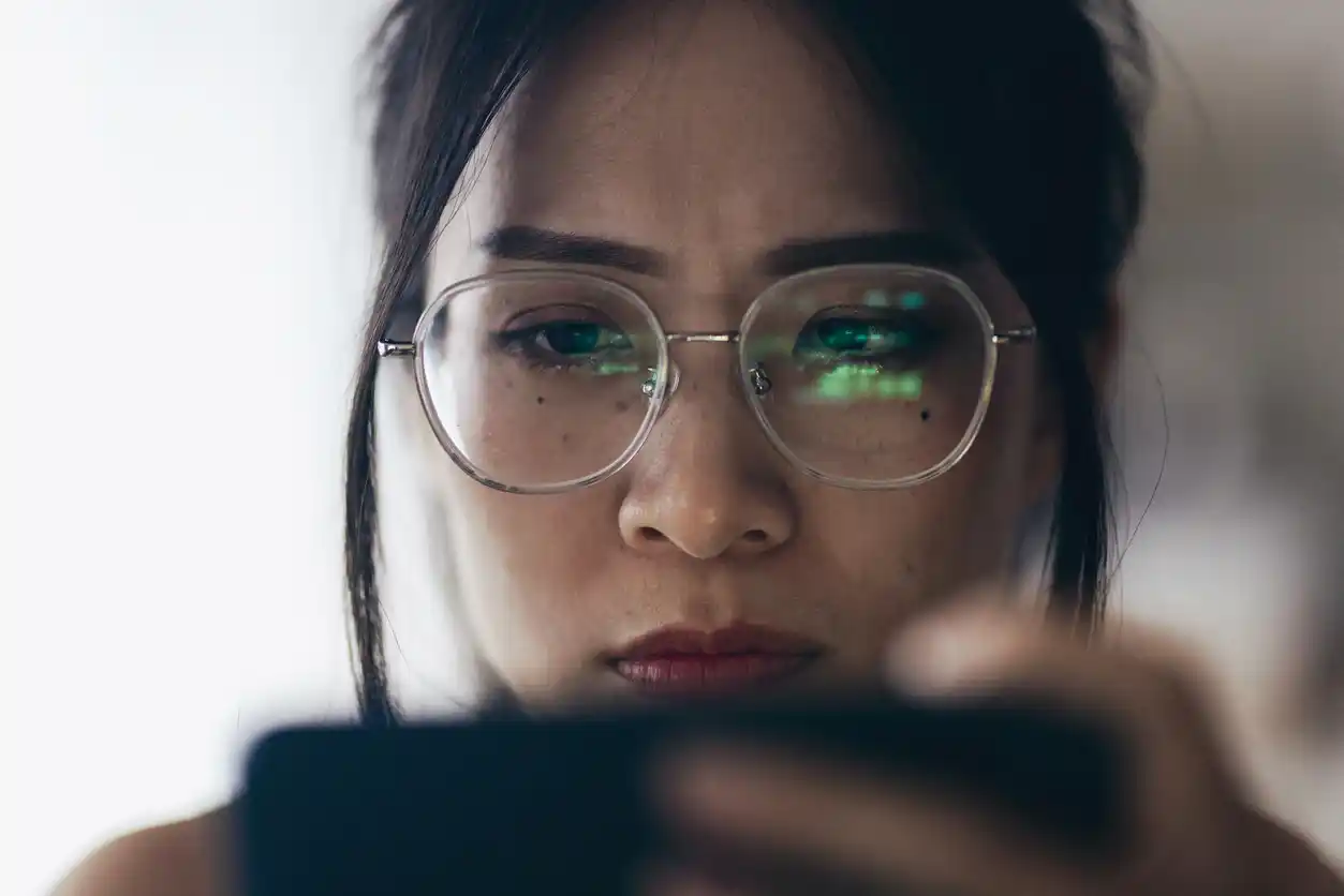 Female crypto copywriter looking at iPhone screen.
